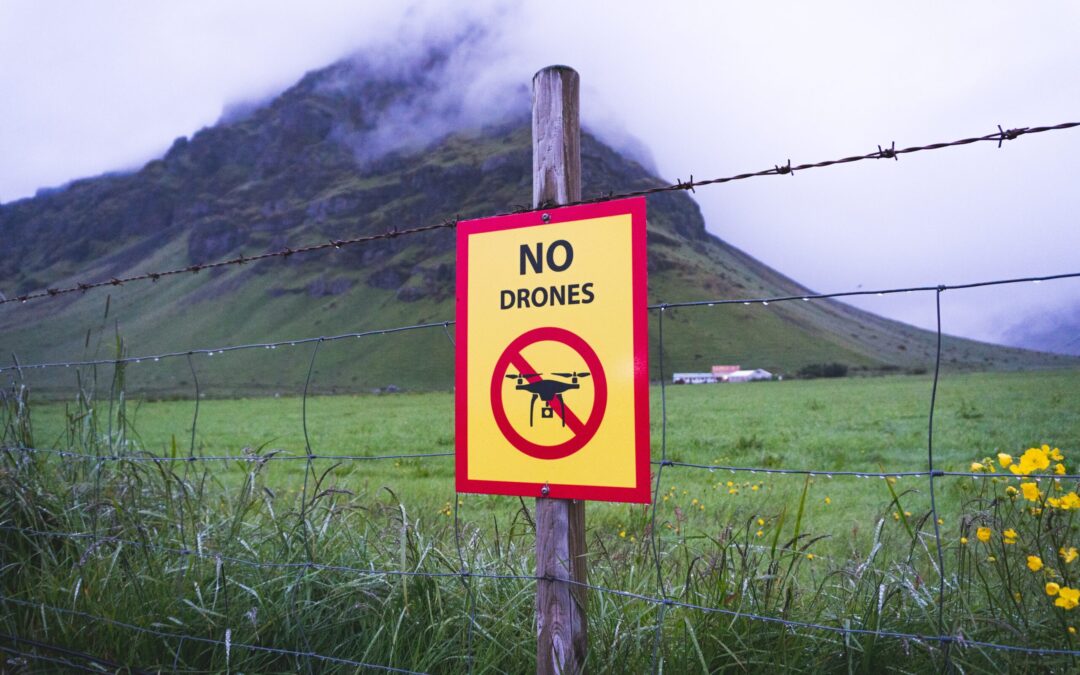 No drones warning sign on a rural fence near a mountain landscape representing restricted airspace and 2024 NDAA drone compliance