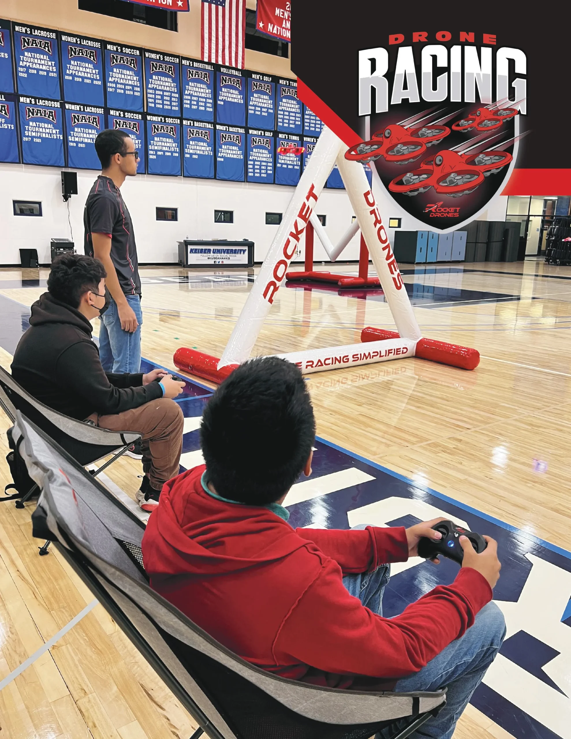 Students flying FPV drones through Rocket Drones racing gates during indoor drone competition and training session.