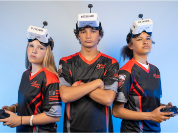 Three Rocket Drones national league pilots wearing FPV headsets and racing jerseys posing for the STEM drone championship.