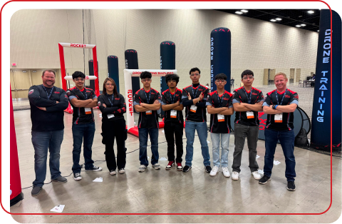 Rocket Drones racing team pilots at indoor training facility with drone racing course in background