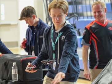 Students learning drone flight in a hands-on Rocket Drones training session, guided by an instructor.